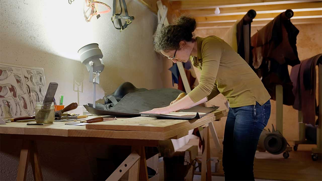 Une femme découpe du cuir dans son atelier