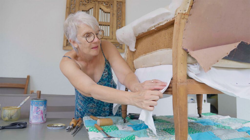Une femme répare un fauteuil ancien